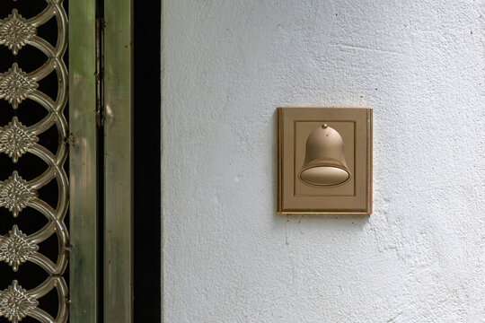 Close-up of a modern, golden color doorbell push button system mounted on a wall, an electrical switch used by a visitor to activate an audible chime inside a home or building.
