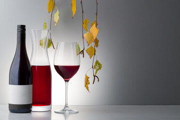 bottle of red seasoned wine, an empty glass autumn leaves with copy space for your text