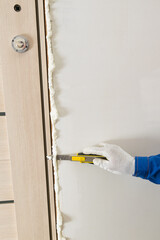the process of cutting dried mounting foam with a stationery knife from a doorway