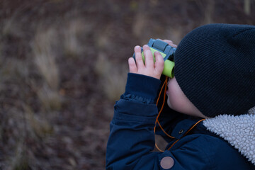 Child using toy binoculars outdoors during nature exploration