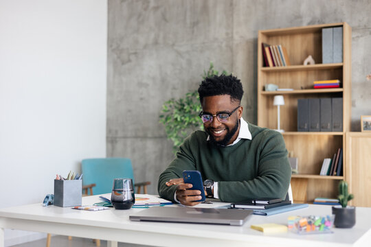 African american man using smartphone in modern office