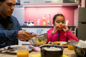 Father and daughter enjoying a family meal together at home, creating a bonding experience over a delicious dinner in their bright kitchen