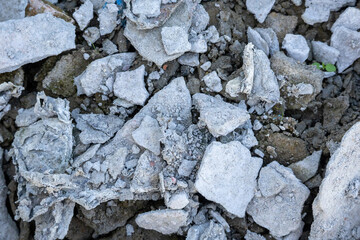 Close-up, abstract background texture of a large, rough pile of broken construction materials, including dried plaster and fractured cement with pieces of brick debris. Decay concept.