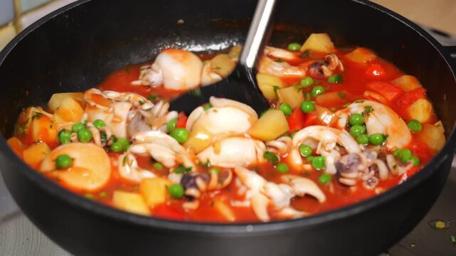 Il cuoco controlla la cottura delle seppie con patate e piselli, pio ricopre la pentola con il coperchio