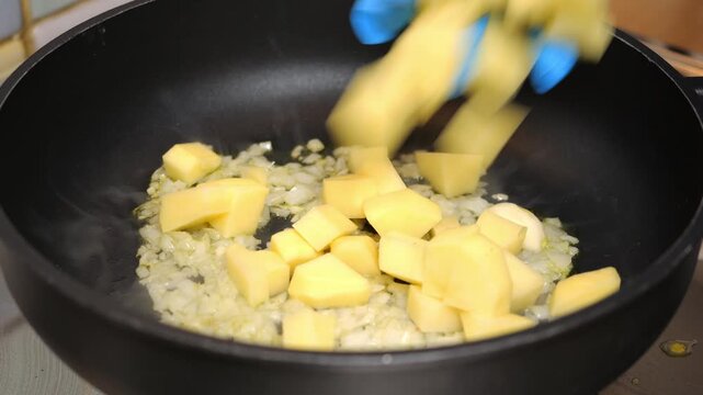 Cuoco mette le patate nella pentola e le mescola 
