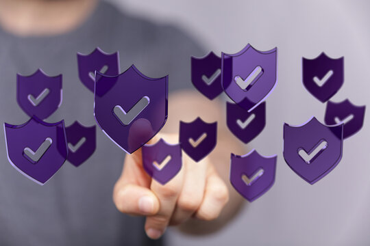 A person's hand interacting with a collection of digital shields, symbolizing data protection, security, and verification. Concept of