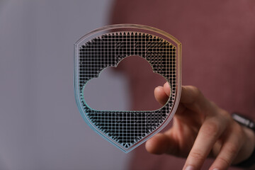 Hand holding cloud symbol inside a shield, digital design of data protection and security. Cloud...