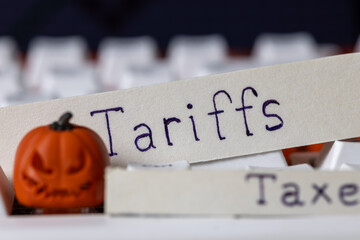 tariffs and taxes written on paper strips with a spooky halloween pumpkin on a white computer keyboard, symbolizing trade policy, international economics, and finance