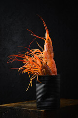 A metal can or bowl of shrimp. Boiled shrimp ready to eat. On a black slate background.