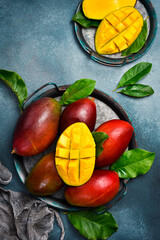 Ripe whole red mango fruits with leaves on a metal tray. Top view. Close-up.