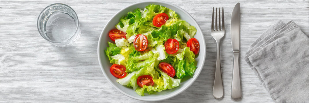 Appetizing healthy salad meal with fresh lettuce and tomato in bowl. delicious vegetarian food for clean diet lunch or dinner, seen from top view on white table - Powered by Adobe
