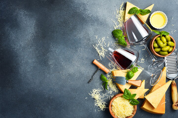 Pieces of hard aged cheese and glasses of red wine. Top view. Food background, free space for text.