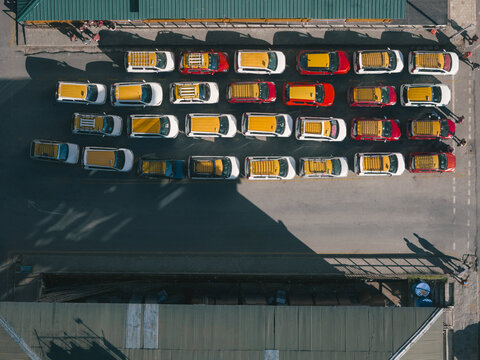 Aerial view of tightly-packed colorful cabs/taxis bask in the sun's glow, casting long shadows across the parking lot, Thimphu, Bhutan.