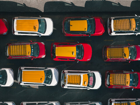 Aerial view of vibrant red and yellow cabs/taxis parked tightly create a striking geometric pattern on the dark asphalt, Thimphu, Bhutan.