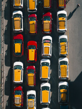 Aerial view of a dense grid of taxis, their yellow tops and red bonnets creating a vibrant, patterned mosaic on the dark asphalt, Thimphu, Bhutan.