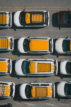 Aerial view of taxis lined up, their bright yellow roofs contrasting sharply against the dull grey asphalt, creating a vibrant urban mosaic, Thimphu, Bhutan.
