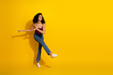 Young woman dancing against a vibrant yellow background in casual chic outfit smiling with energy and style for lifestyle fashion stock