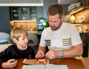 Young father with a cute 6-year-old son playing together building blocks at home.