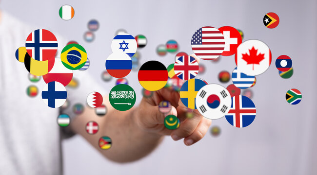 Person touching and pointing at a collection of international flags, symbolizing global connection and international relations. Suitable for con