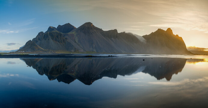 panorama view of Iceland's iconic Vestrahorn mountain with reflections in the tidal pools just after sunrise