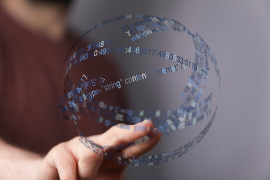 Abstract image of a person's hand holding a digital globe made of code, symbolizing the internet, data and technology.