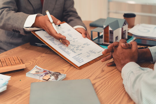 Real estate agent and client sign contract on clipboard on table after signing real estate sales contract along with approved home loan application form.