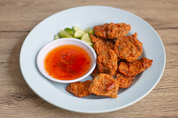 Fried fish cakes served with dipping sauce and sliced ​​cucumber, served on a plate. Central Thai food.