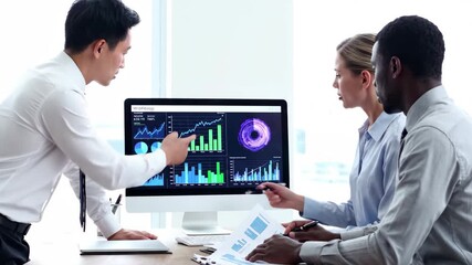 Diverse business team collaborating and discussing financial data and analytics on a monitor in an office - Powered by Adobe