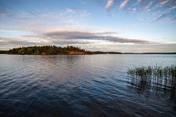 An island on a lake under a cloudy sky on an early summer morning
