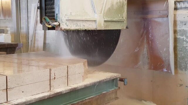 D&eacute;coupe d'un bloc de calcaire issu d'une carri&egrave;re, &agrave; l'aide d'une scie circulaire et sous aspersion d'eau.