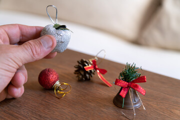 Hand holding a silver glitter apple ornament, preparing various decorations for festive season