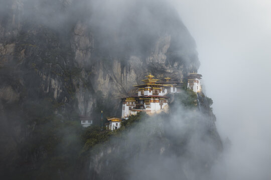 Aerial view of the iconic Tigers Nest monastery clinging to a steep cliffside shrouded in ethereal mist, a testament to faith and architecture, Paro, Bhutan.
