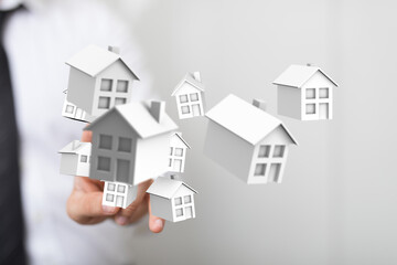 A hand interacting with miniature houses, symbolizing concepts like homeownership, real estate market, and property investment. Perfect for arti