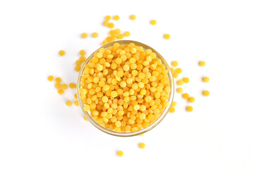 Yellow bulgur grain lies in and around a glass bowl.