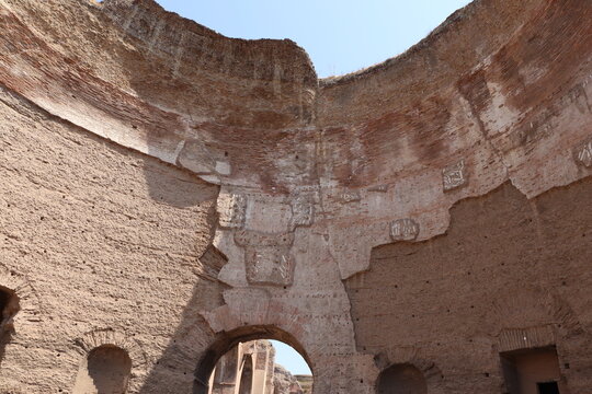 Baths of Caracalla, A dramatic interior view of the circular, vaulted ruins with towering textured brick walls and a deep central archway