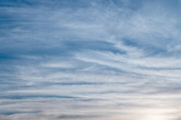 A tranquil blue sky filled with wispy clouds above a calm horizon