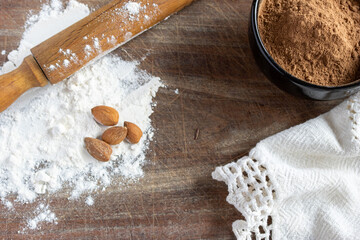 Baking still life, cocoa powder, white flour, walnuts and rolling pin on rustic wooden surface. Copy space