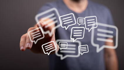 Close up of a man's hand interacting with digital speech bubbles. Concept of communication, social media and online messaging.