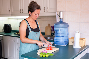 Woman preparing healthy meal chopping fresh vegetables in kitchen