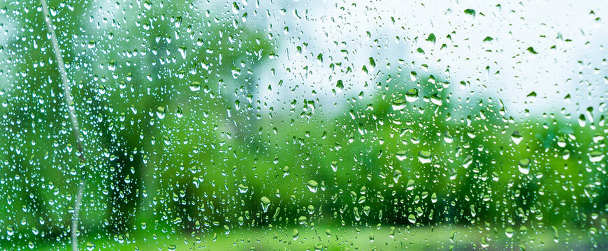 A rainy day window view. Rain drops on window. Condensed rain drop on the car glass window on a rainy day. Dew moisture condensation on wet mirror background. Fresh weather. Water raindrop bg