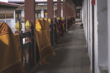 Gangtey, Bhutan - 20 September 2025: View of vibrant yellow and maroon fabrics draped along the wooden corridor of Gangtey Monastery, contrasting against the white walls and red pillars.