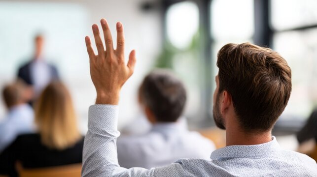 Man raising hand asking question during seminar, participating in conference, training, or educational event