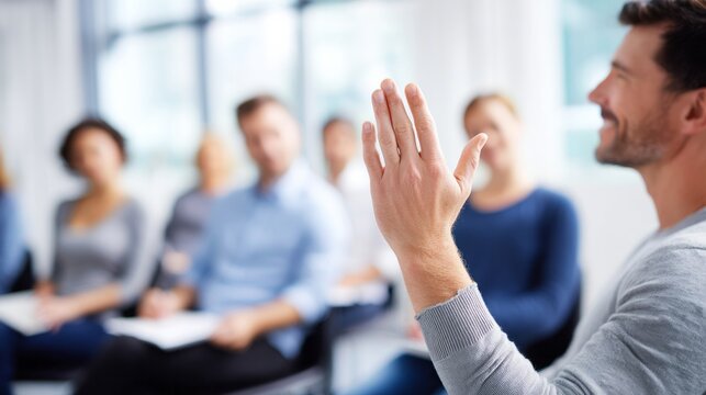 Man raising hand asking question or participating in group discussion, workshop, seminar or business meeting