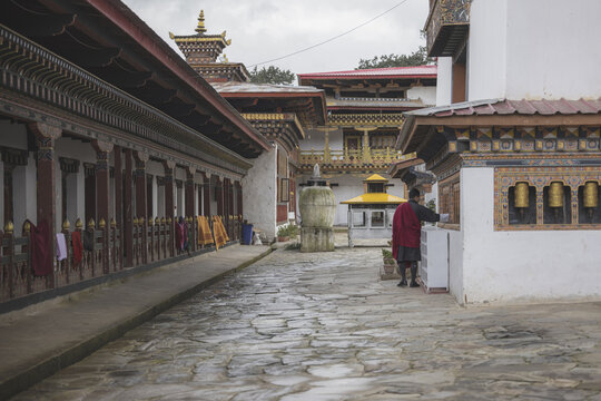 Gangtey, Bhutan - 20 September 2025: View of the monastery's stone pathway, where the warm wood tones contrast with the cool stone, and the rhythmic arrangement of prayer wheels.