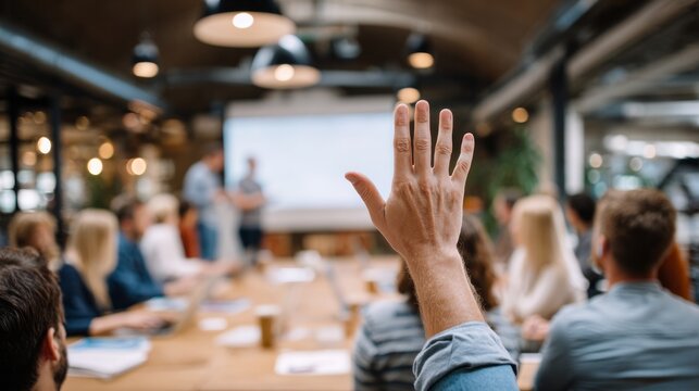 Raised hand from audience member actively participating in a business meeting, asking a question during a corporate presentation