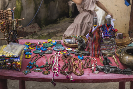 View of colorful jewelry, prayer beads, and carved figures displayed on a red table, creating a vibrant marketplace scene, Sopsokha, Punakha, Bhutan.