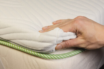 Hand is touching very soft orthopedic topper mattress.
