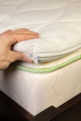 Hand is touching mattress filled with coconut chips. Firm orthopedic mattress topper. Vertical photo.