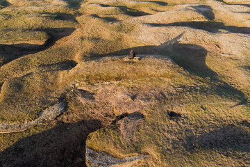 Aerial view of a person sitting on a bench in the unique grassy Kostivere karst landscape in Estonia