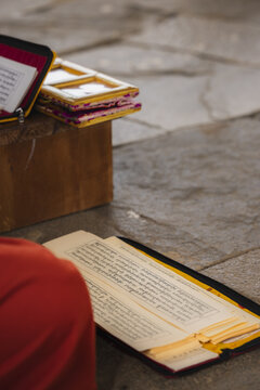 View of opened religious text with gilt edges and prayer book on a stone surface with brick, illuminating ancient wisdom, Wolakha Nunnery, Punakha, Bhutan.